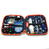 Open navy sewing kit with white stars, orange trim, contains thread, needles, scissors, thimble, tape measure. Prym logo. 651242