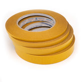 Pila de rollos de cinta adhesiva de doble cara amarilla con marca Serafini y texto 'Made in Italy' en el núcleo de cartón. SERAFINI-TAPE-20MM