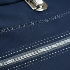 Close-up van donkerblauwe stof met witte stiksels, een rits en een metalen sluiting, demonstrerend de sterkte van Gutermann naaigaren. GUTERMANN-STERK-SET-734528 | GUTERMANN-STERK-SET-734528