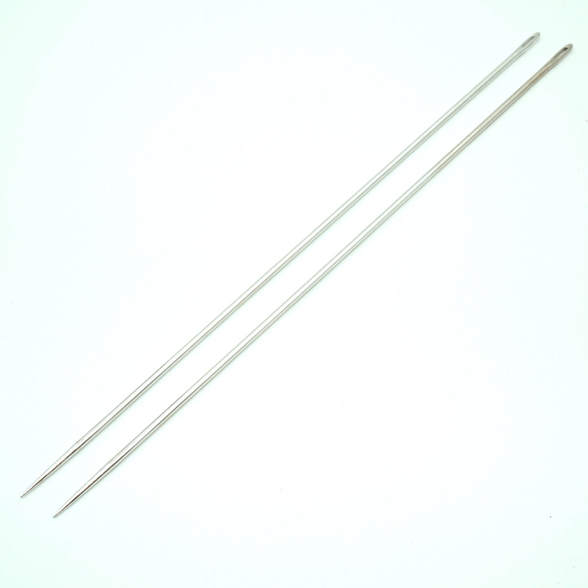 Twee lange, zilverkleurige Prym matrasnaalden van 25 cm, diagonaal liggend op een witte achtergrond. | PRYM-131490