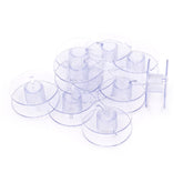 Stapel durchsichtige Plastiknähmaschinenspulen mit gerippten Mittelstücken, auf weißem Hintergrund. SEWMATE-55623P 4714379452532