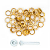 Pile of 24 gold metal eyelets, 8mm diameter, with a metal stamping tool. ZEILRING-FK-8-GOUD